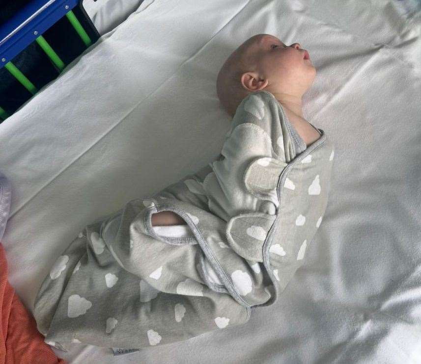 Matilda in a hospital bed, doing what her mum, Morgan, has called the 'banana pose'