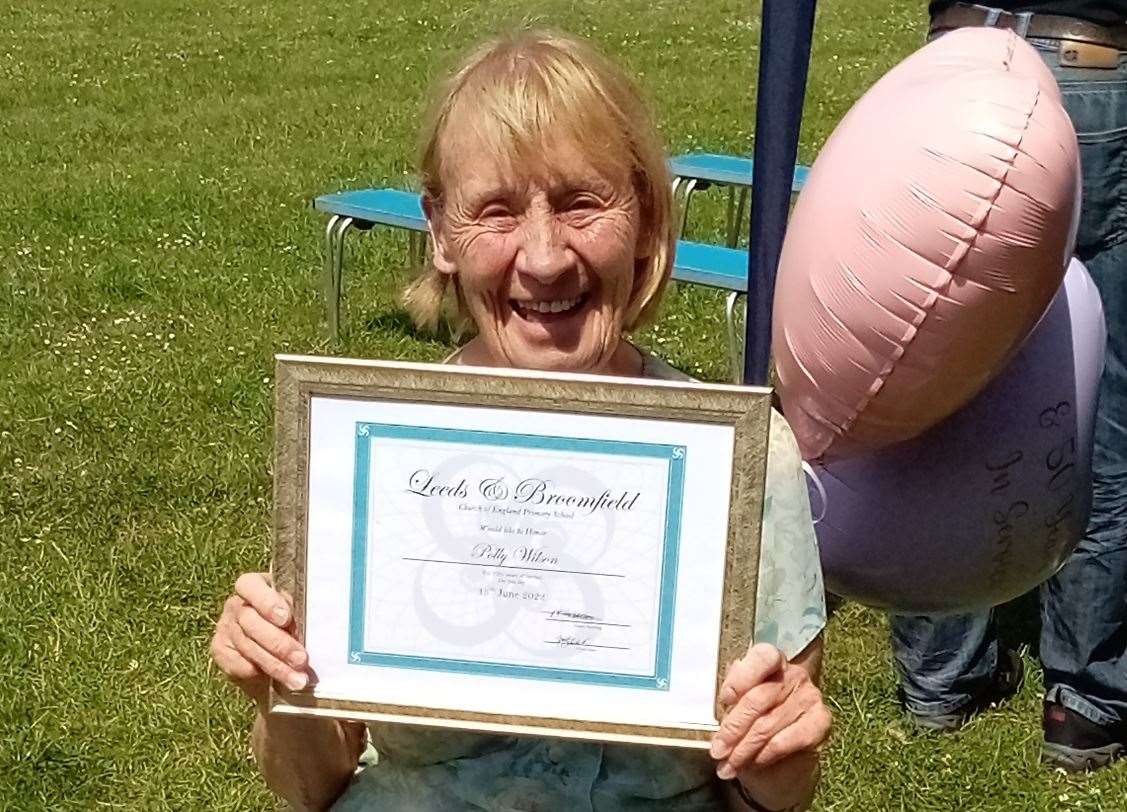 Polly posing with her plaque celebrating 50 years of service at Leeds and Broomfield Church of England School. Picture: Sharon Clark