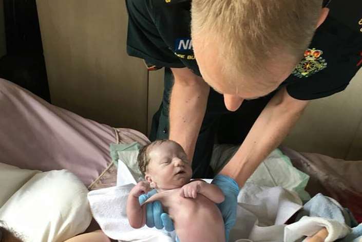 The paramedic hands baby Cassie to her mum